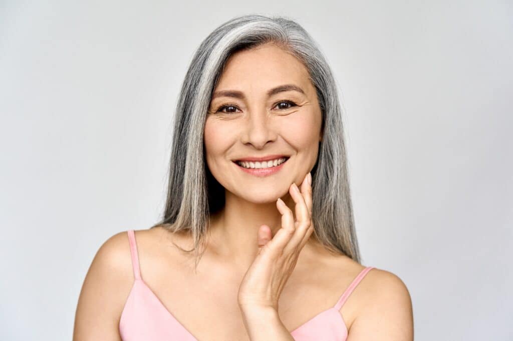 A woman smiling and showing the results of Thermage® skin tightening
