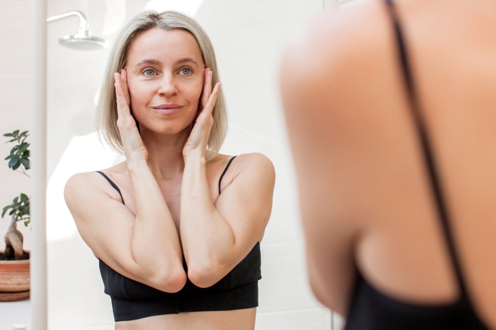 A woman looking in the mirror considering a facelift in Cleveland